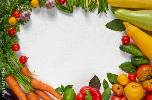 Various healthy vegetarian food background. Frame of organic raw vegetables  herbs and spices on the white table  cherry tomatoes  zucchini  beet  garlic  cabbage  basil. Top view with copy space