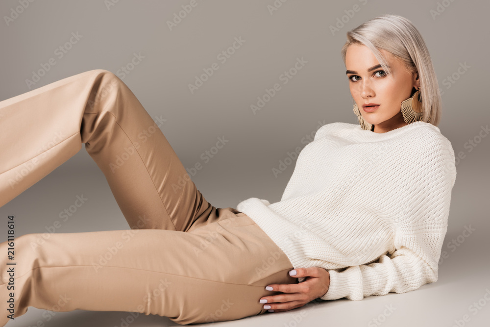 © LIGHTFIELD STUDIOS - elegant blonde woman lying in white sweater and beige pants, on grey © LIGHTFIELD STUDIOS - elegant blonde woman lying in white sweater and beige pants, on grey