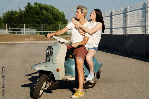 young beautiful couple in love riding on old scooter. adventure and vacations concept. motorbike, summer, traveling, romance, smiling, happy, having fun, stylish outfit, date, enjoying in trip