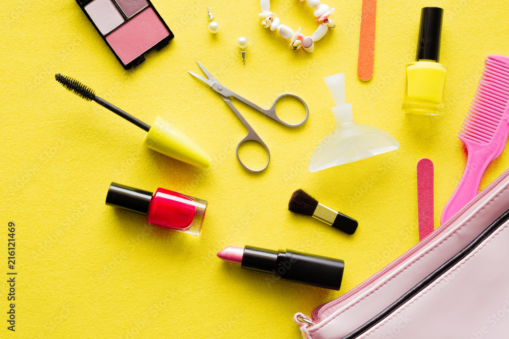 Various decorative makeup cosmetics with bag on yellow background. Simple set of nails care. Different, colorful beauty essentials for women. Mockup for special offers as advertising. Flat Lay. Various decorative makeup cosmetics with bag on yellow background. Simple set of nails care. Different, colorful beauty essentials for women. Mockup for special offers as advertising. Flat Lay.