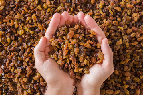 Woman's hands holding different, colorful raisins. Dried grapes. Healthy, sweet food. Top view.