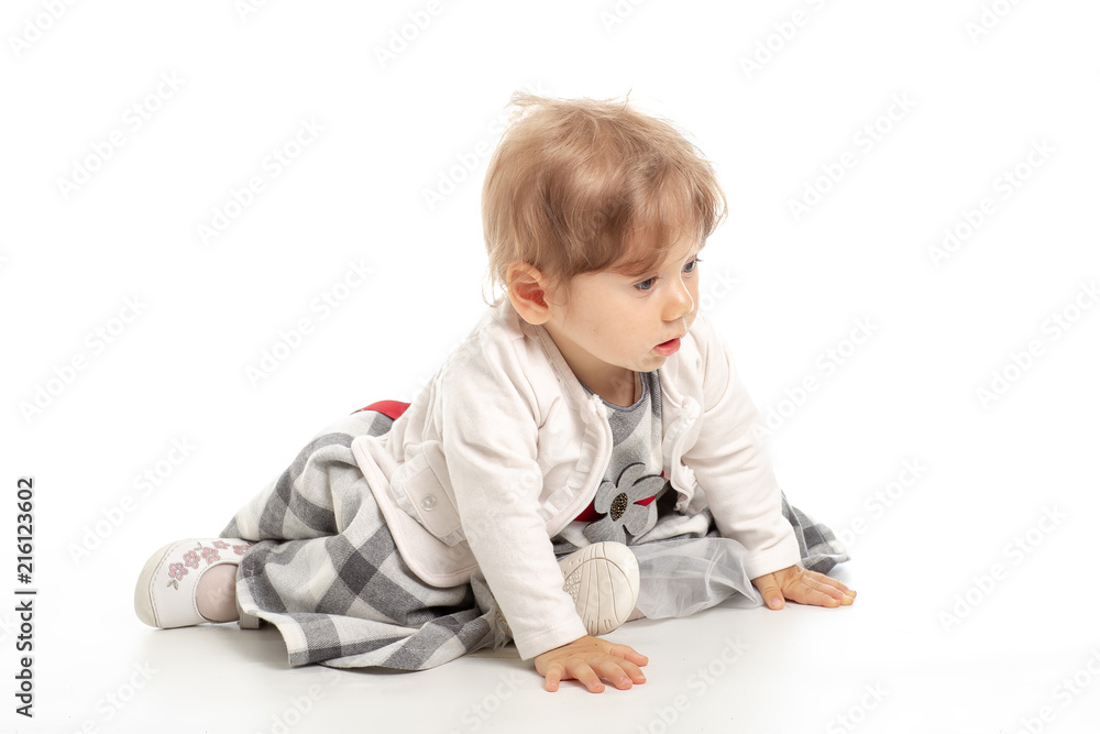 Elegant baby girl 1 year old sitting on the studio floor. White Background. Elegant baby girl 1 year old sitting on the studio floor. White Background.