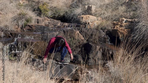 Woman sitting on rocks by a waterfall in Dullstroom South Africa photo