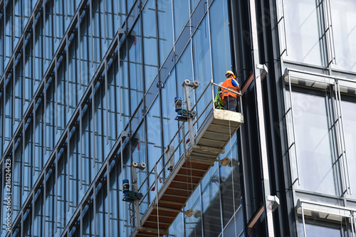 Obraz na plátně Construction workers on a suspended platform on a skyscraper