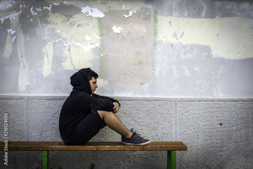Little boy sad sitting alone at school hides his face