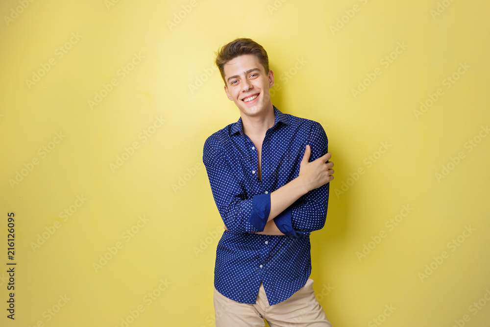 Obraz premium Friendly looking cheerful european guy wearing blue shirt smiling standing over yellow background