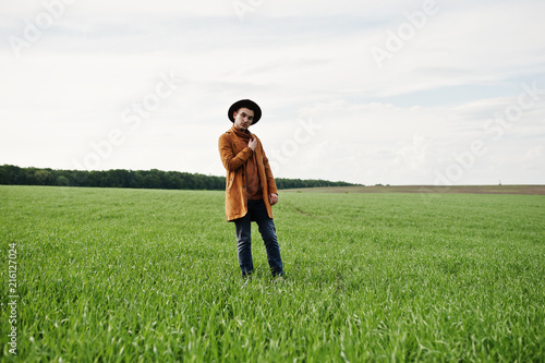 Stylish man in glasses, brown jacket and hat posed on green field. © AS Photo Family