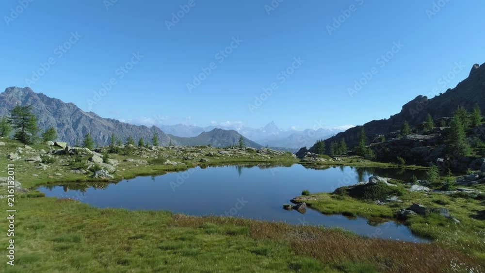 moving forward above clear blue lake and pine woods in sunny summer day.Europe Italy Alps Valle d'Aosta outdoor green nature scape mountains wild aerial establisher.4k drone flight establishing shot moving forward above clear blue lake and pine woods in sunny summer day.Europe Italy Alps Valle d'Aosta outdoor green nature scape mountains wild aerial establisher.4k drone flight establishing shot