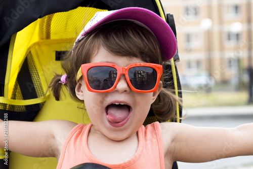 Little fashion pretty girl in orange sunglasses very happy with something