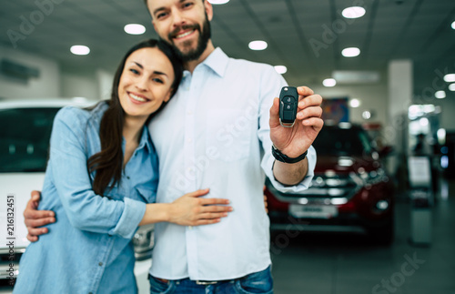 Happy young couple chooses and buying a new car for the family.