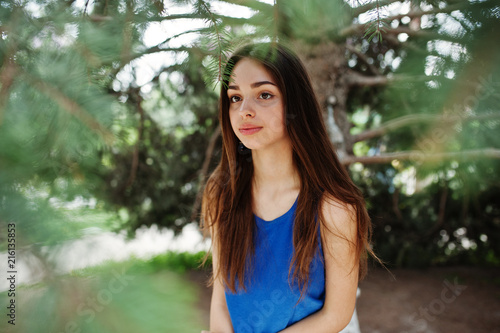 Teenage girl in blue dress posed outdoor at sunny day.