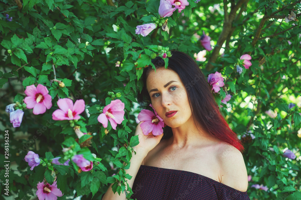 Naklejka premium Beautiful girl in the garden with flowers . Portrait of a young girl in a summer Park
