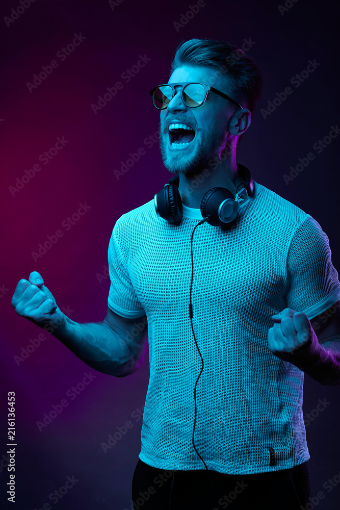 Neon portrait of screaming man with headphones on neck, in yellow glasses, white t-shirt Neon portrait of screaming man with headphones on neck, in yellow glasses, white t-shirt