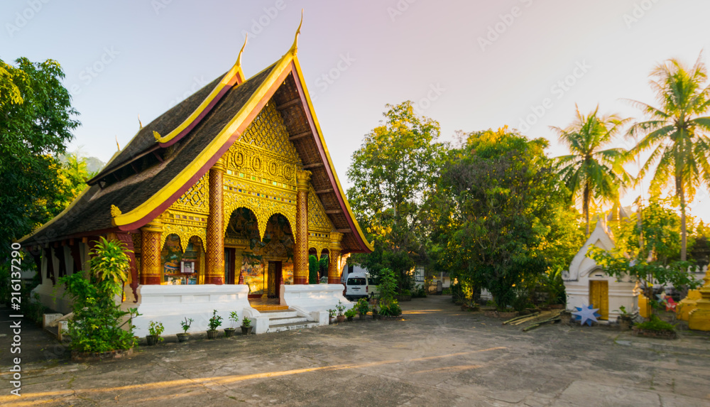 Buddhist temple with golden carved decorations and tiled roof in Vientiane, Laos