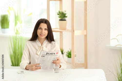 Young woman reading newspap...