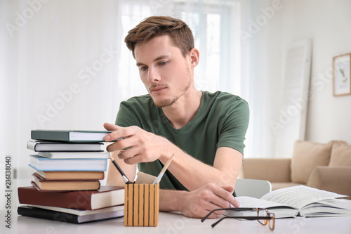 Young man reading books at ...