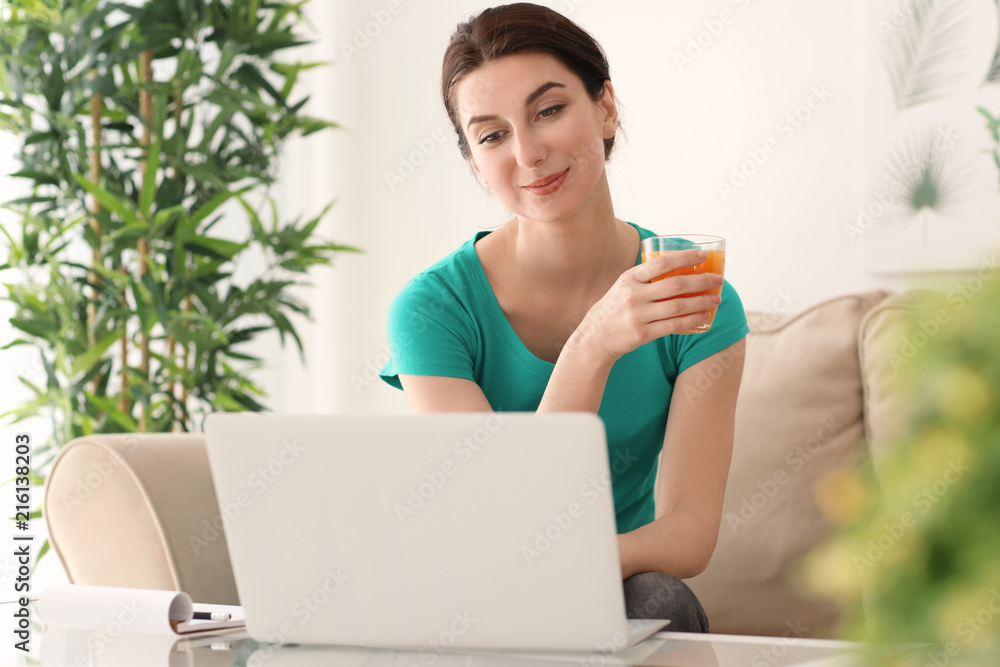 Young female freelancer drinking juice while working with laptop at home Young female freelancer drinking juice while working with laptop at home
