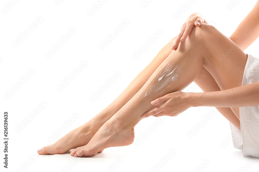 Young woman applying cream onto her leg after depilation on white background Young woman applying cream onto her leg after depilation on white background