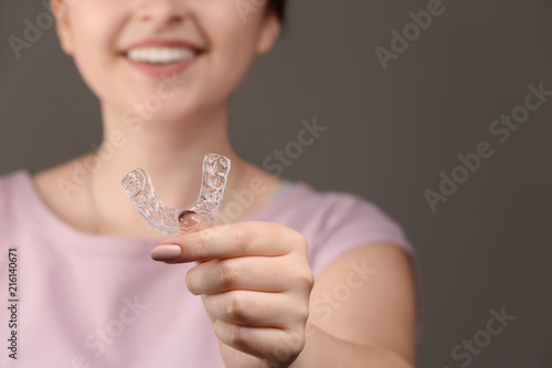 Woman with occlusal splint on grey background, closeup