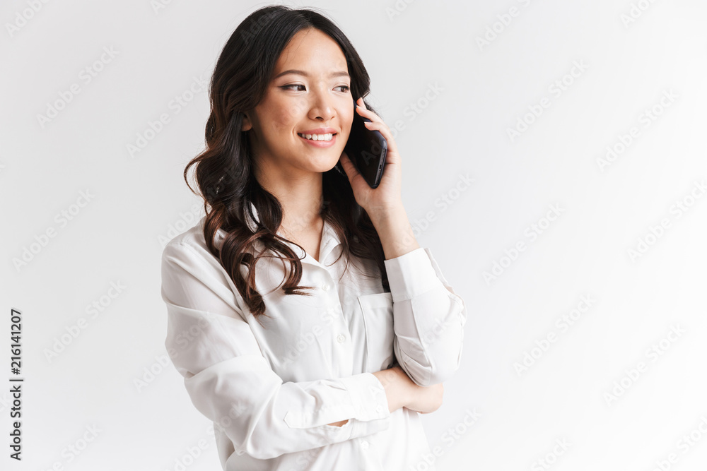 Photo closeup of beautiful chinese woman with long dark hair holding smartphone and having mobile call, isolated over white background in studio Photo closeup of beautiful chinese woman with long dark hair holding smartphone and having mobile call, isolated over white background in studio