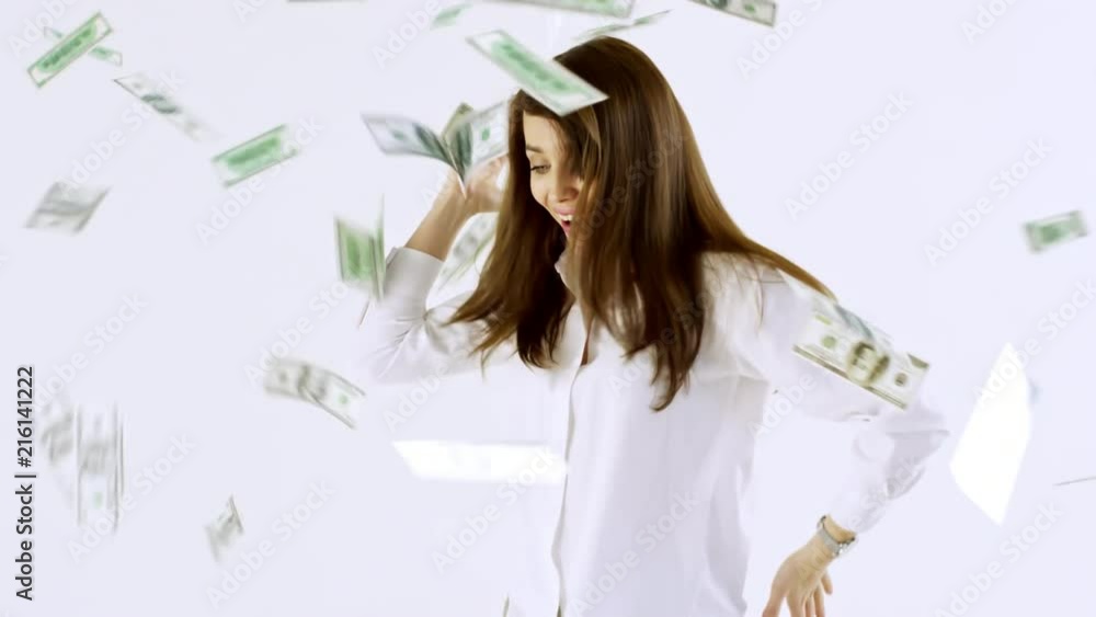 Studio shot of happy young businesswoman in shirt dancing isolated on white background and celebrating as money falling on her from above Studio shot of happy young businesswoman in shirt dancing isolated on white background and celebrating as money falling on her from above