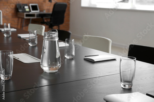 Fotografie Table with jug of water and glasses prepared for business meeting in conference