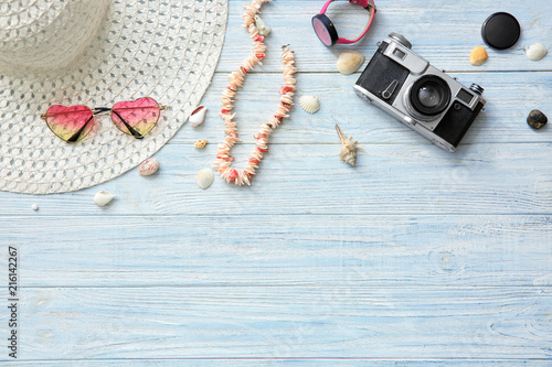 Composition with photo camera, seashells and female accessories on wooden background