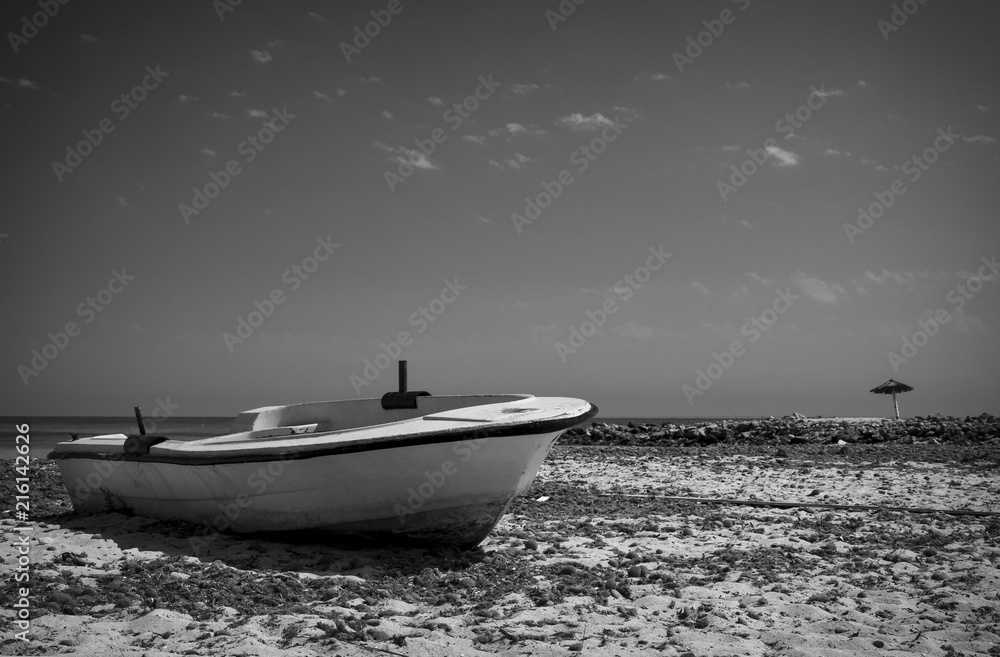 Naklejka premium Wooden boat in the sand of the beach and with a tropical landscape.Photo black and white contrast.