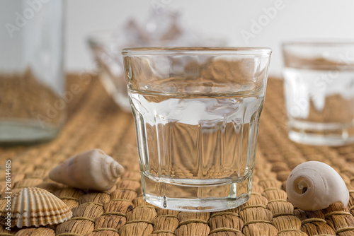 Glasses and bottle of traditional drink Ouzo or Raki with anise star seeds on natural matting