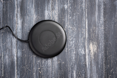 Wireless charger for mobile phone on vintage wooden gray background, top view