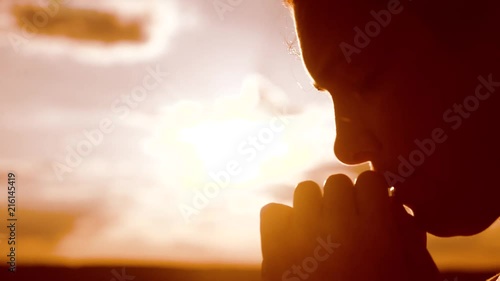 the girl prays. Girl folded her hands in prayer silhouette at sunset. slow motion video. Girl folded lifestyle her hands in prayer pray to God. girl praying asks forgiveness for sins of repentance photo