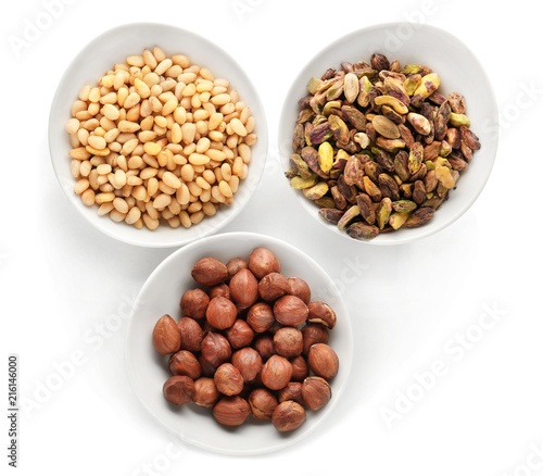 Bowls with tasty nuts on white background
