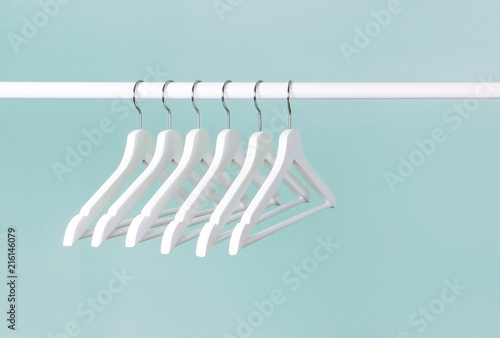 Canvas Print Many wooden white hangers on a rod, isolated on blue turquoise wall background