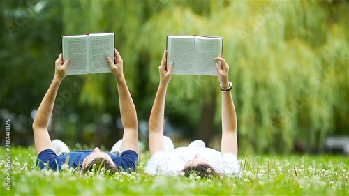 Relaxed young couple reading books while lying on grass
