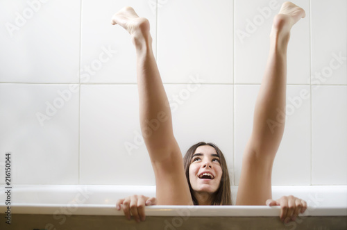 Girl sitting in the bath with her legs in the air photo