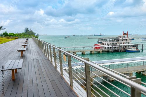 Boardwalk by harbor with ships
