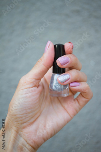 Pink manicure with silvery details. A bottle of silvery nail polish