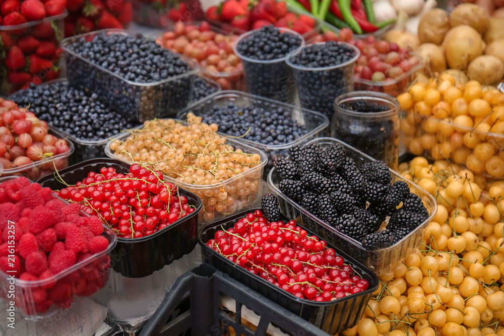 Containers with different ripe berries at market