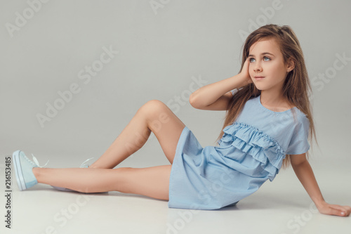 little fashionable girl posing in summer blue dress in studio