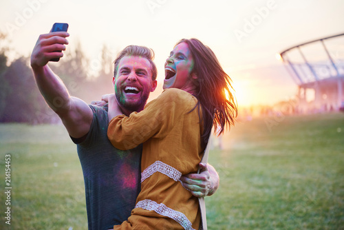 Young couple covered in coloured chalk powder taking selfie at Holi Festival photo