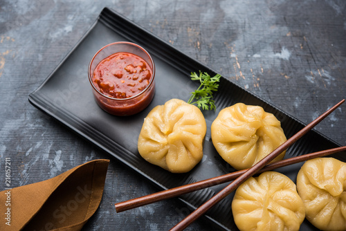 Traditional dumpling momos food from Nepal served with tomato chutney over moody background. Selective focus