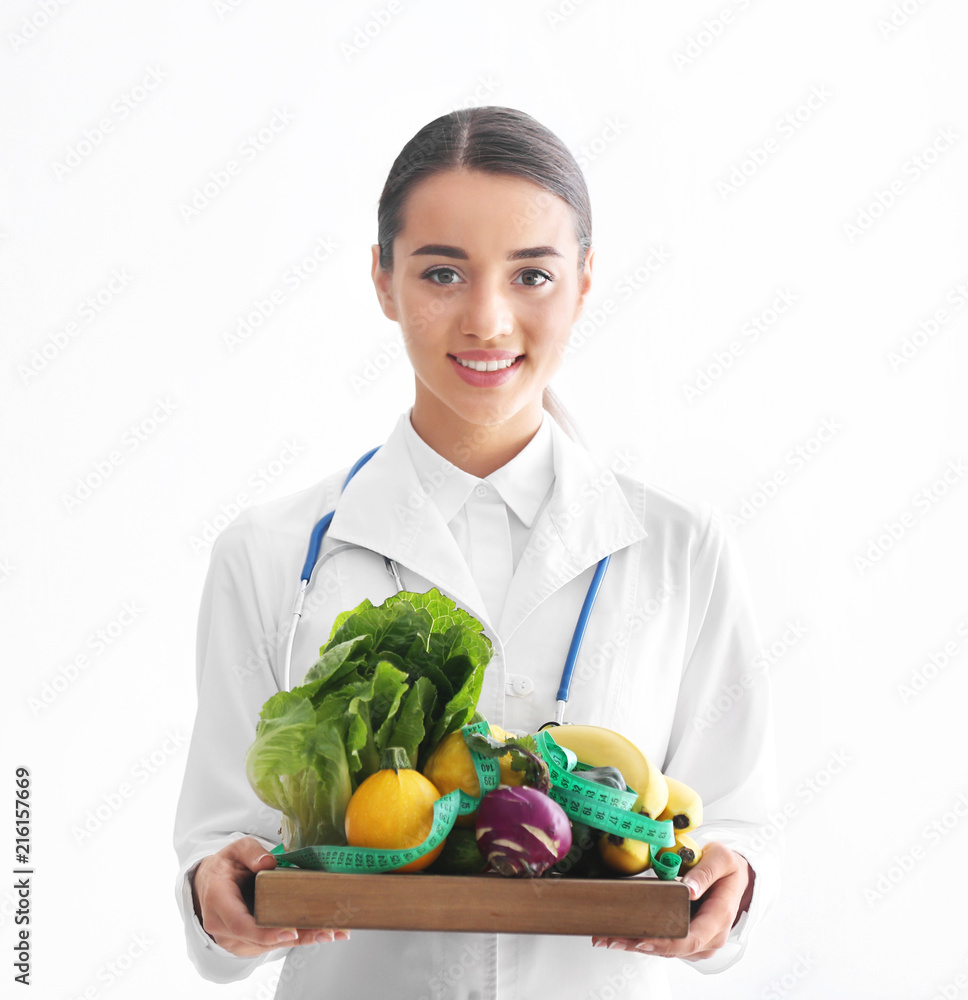 Female nutritionist holding wooden board with healthy vegetables and fruits on white background Female nutritionist holding wooden board with healthy vegetables and fruits on white background