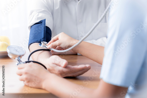 Close-up of nurse with stethoscope checking blood pressure of senior person