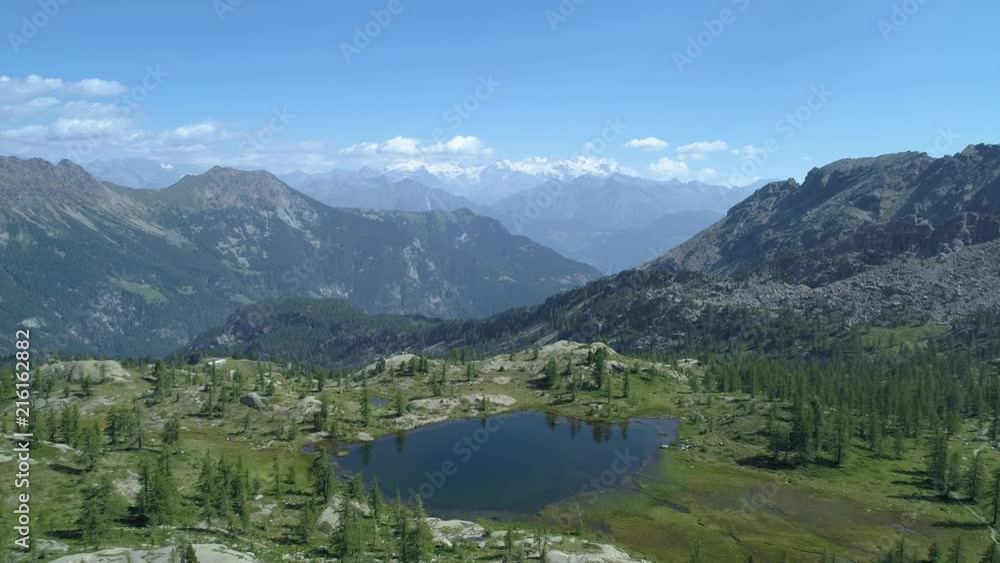 moving forward above clear blue lake and pine woods in sunny summer day.Europe Italy Alps Valle d'Aosta outdoor green nature scape mountains wild aerial establisher.4k drone flight establishing shot moving forward above clear blue lake and pine woods in sunny summer day.Europe Italy Alps Valle d'Aosta outdoor green nature scape mountains wild aerial establisher.4k drone flight establishing shot