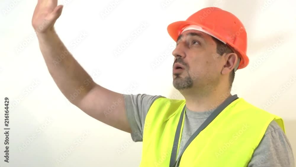 The builder in a protective helmet gives a signal upwards The builder in a protective helmet gives a signal upwards
