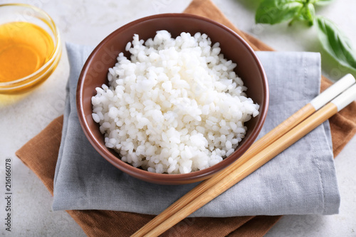 Bowl with boiled white rice on grey table