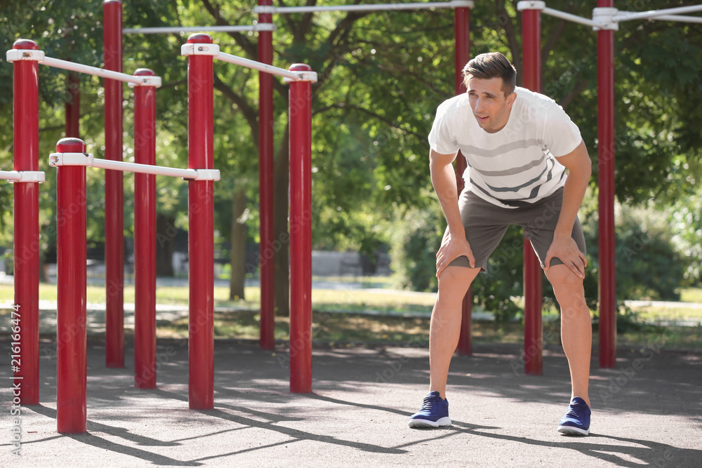 Fototapeta premium Sporty young man resting after training on athletic field outdoors