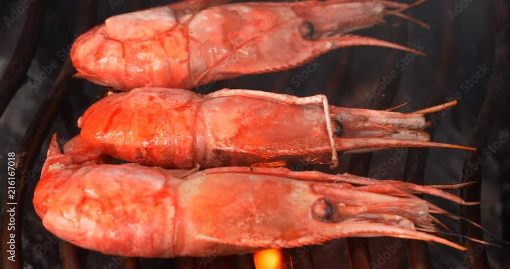 Cinema 4K closeup shot of delicious shrimps on the grill with flames and smoke Cinema 4K closeup shot of delicious shrimps on the grill with flames and smoke