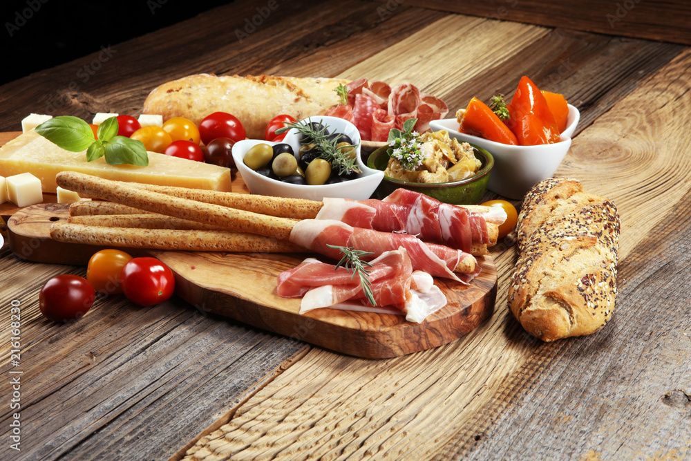 Italian antipasti wine snacks set. Cheese variety, Mediterranean olives, crudo, Prosciutto di Parma, salami and wine in glasses over wooden grunge background. Italian antipasti wine snacks set. Cheese variety, Mediterranean olives, crudo, Prosciutto di Parma, salami and wine in glasses over wooden grunge background.