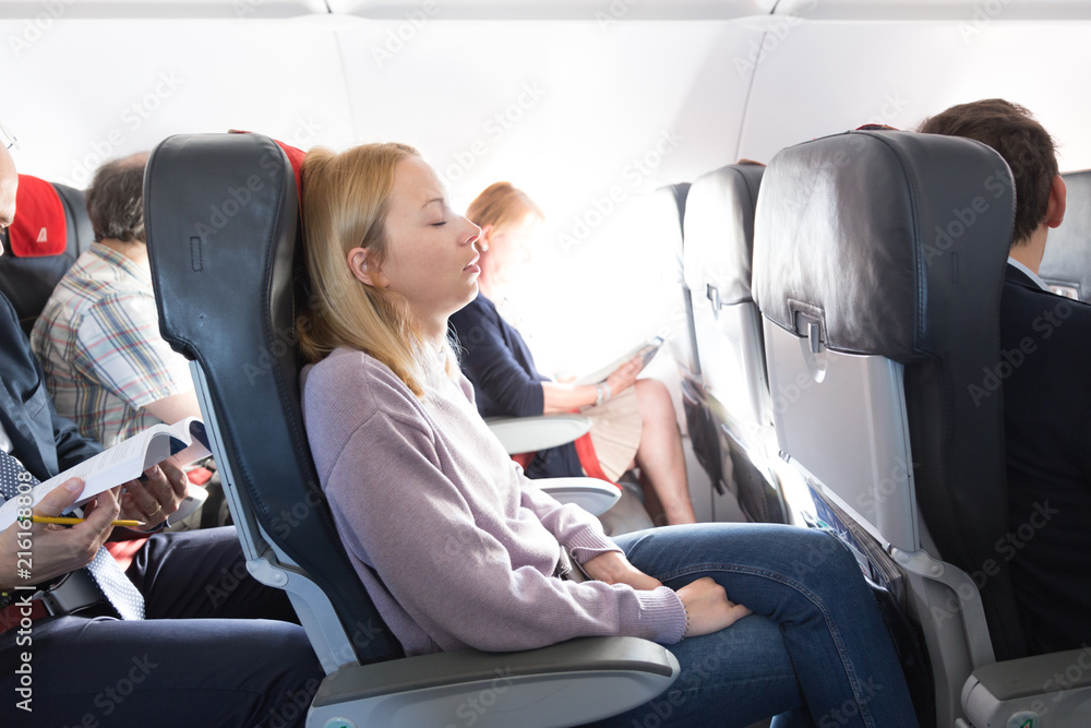 Φωτογραφία Tired blonde casual caucasian woman napping on seat while traveling by airplane